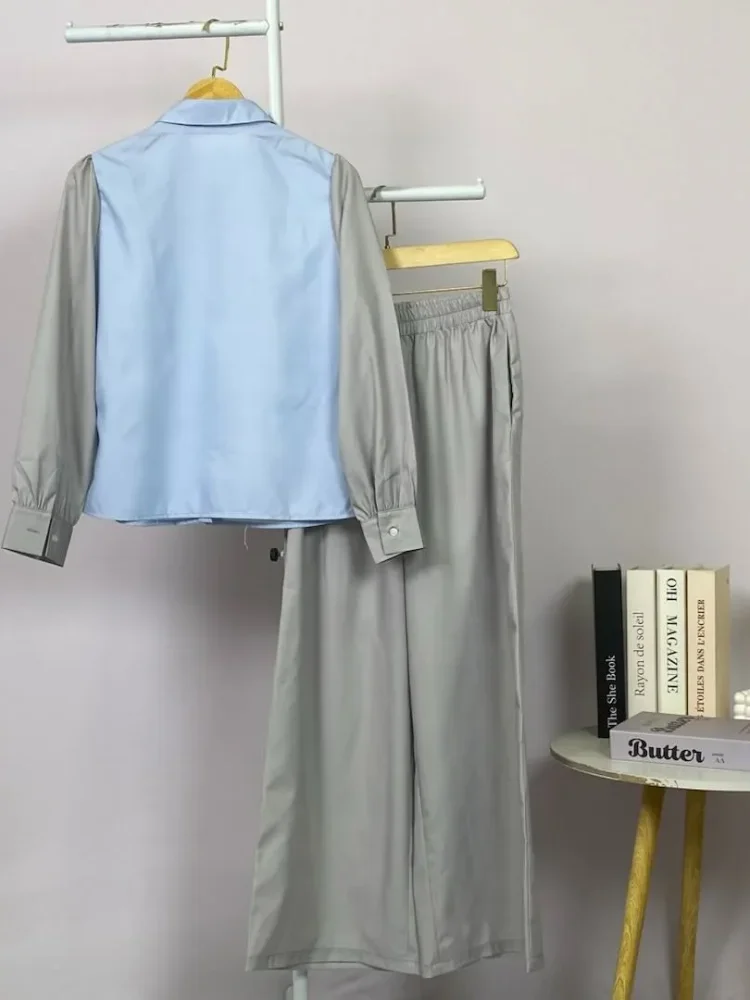 ASAYA Atasan lengan panjang desain braun memiliki efek dua lapis, dipadukan dengan rompi warna kontras dan celana panjang senada, lalu ditumpuk dengan celana panjang setelan tambahan.