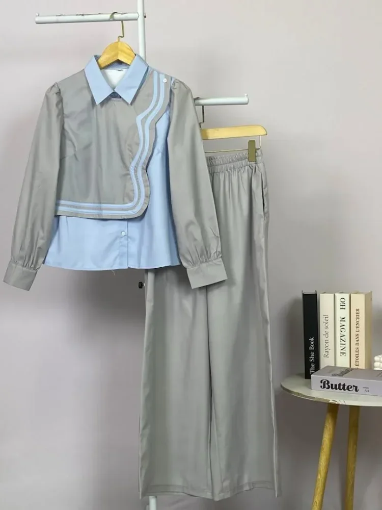 ASAYA Atasan lengan panjang desain braun memiliki efek dua lapis, dipadukan dengan rompi warna kontras dan celana panjang senada, lalu ditumpuk dengan celana panjang setelan tambahan.