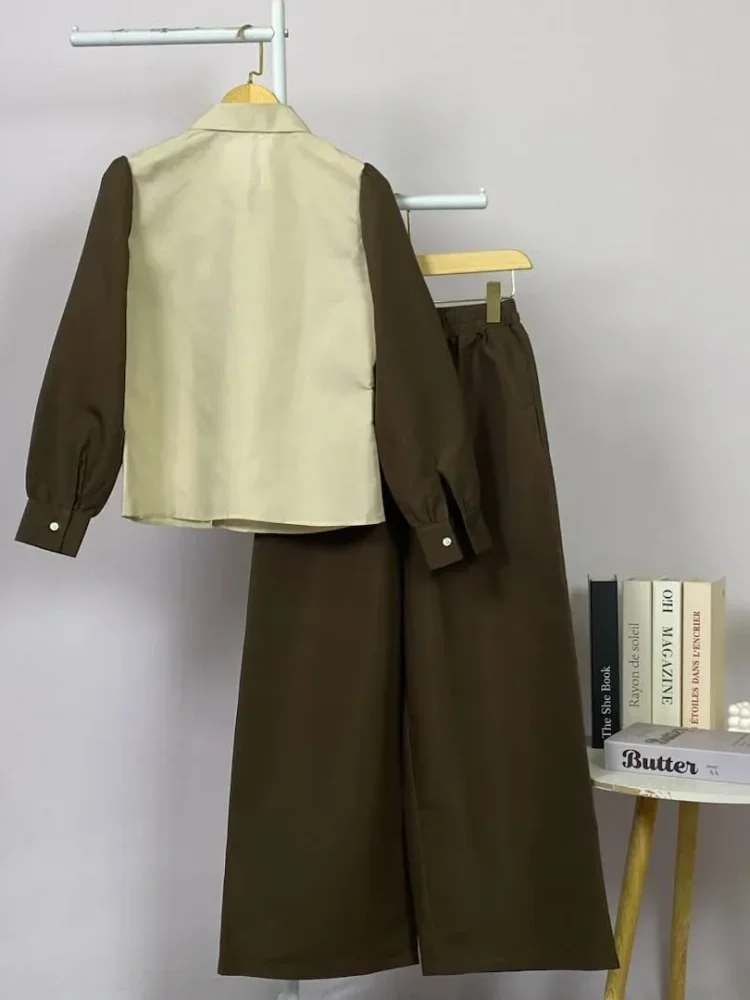 ASAYA Atasan lengan panjang desain braun memiliki efek dua lapis, dipadukan dengan rompi warna kontras dan celana panjang senada, lalu ditumpuk dengan celana panjang setelan tambahan.