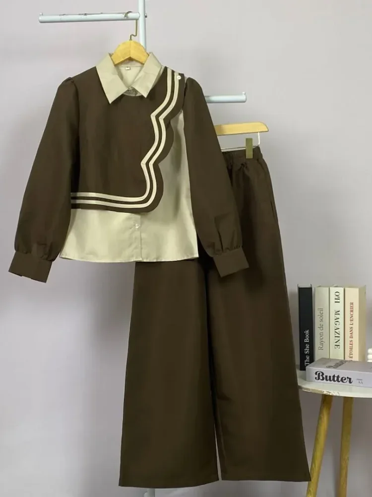 ASAYA Atasan lengan panjang desain braun memiliki efek dua lapis, dipadukan dengan rompi warna kontras dan celana panjang senada, lalu ditumpuk dengan celana panjang setelan tambahan.