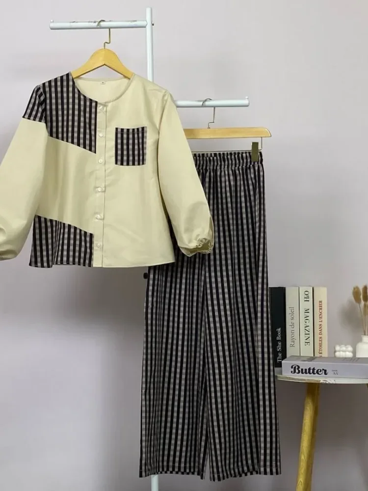 ASAYA Atasan dua potong dengan desain patchwork asimetris dan gaya minimalis, dipadukan dengan celana yang nyaman.