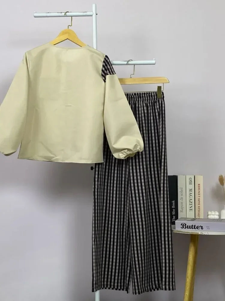 ASAYA Atasan dua potong dengan desain patchwork asimetris dan gaya minimalis, dipadukan dengan celana yang nyaman.